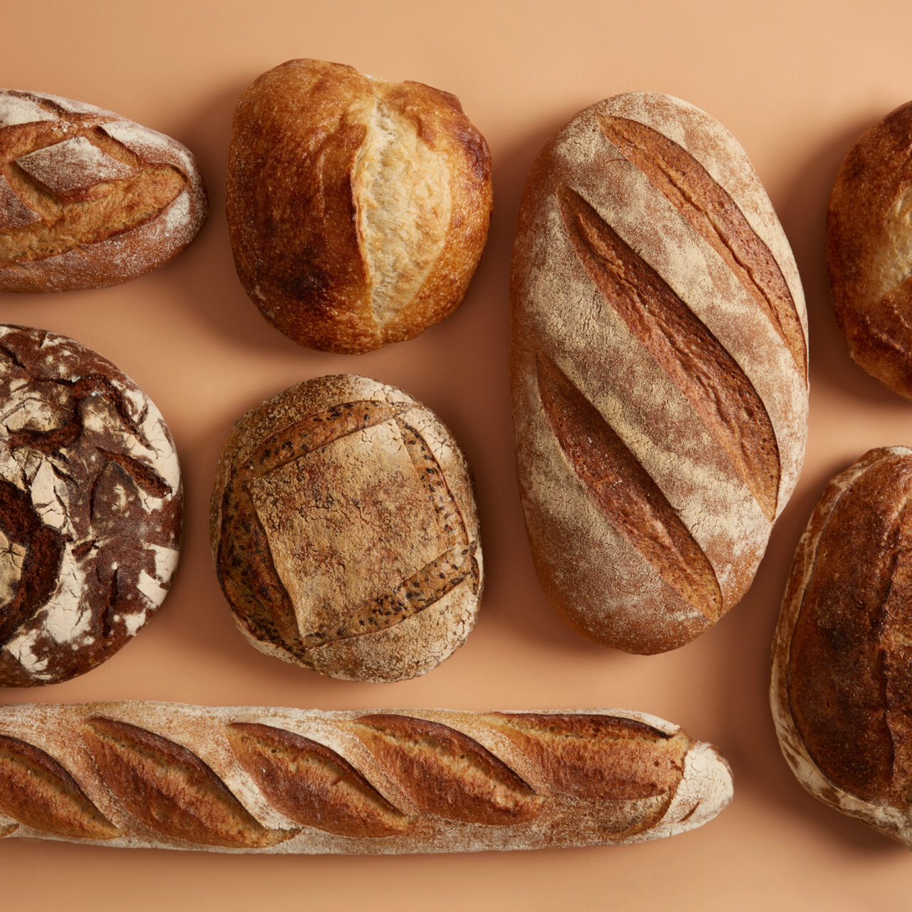 Natural sourdough bread baked with organic flour. Spelt wheat, buckwheat, rye bread isolated over beige background. Bakery and agriculture concept. Nutrient freshly baked products easy to digest