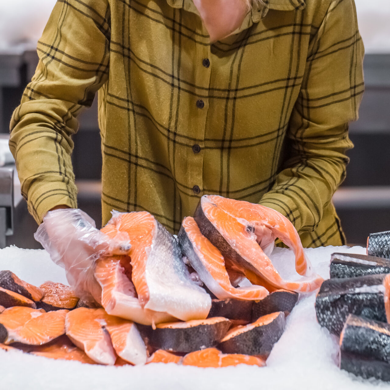 Woman in the supermarket. Beautiful young woman holding a salmon fish in her hands. The concept of healthy eating. Seafood